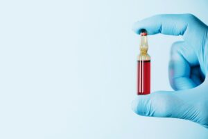 Medicine, injections, vaccination concept. Hands in medical gloves holding ampoule with vitamin B on