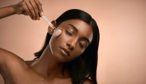 Shot of an attractive young woman using a derma roller against a brown background
