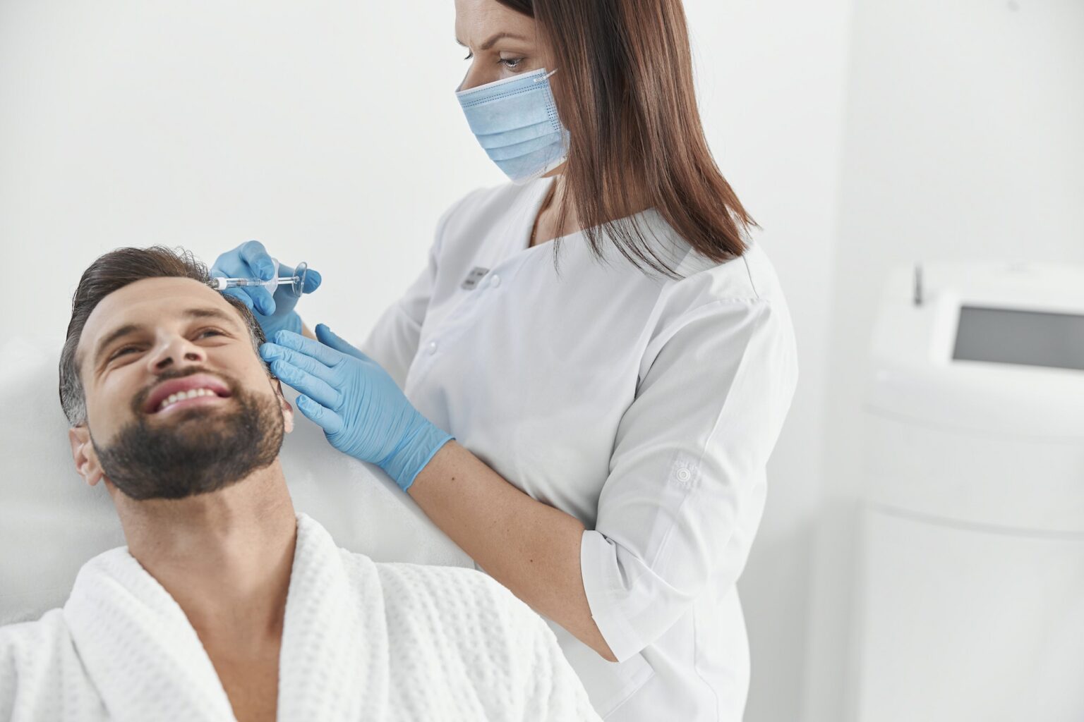 Smiling man with beard undergoes meso therapy procedure with professional cosmetologist in clinic